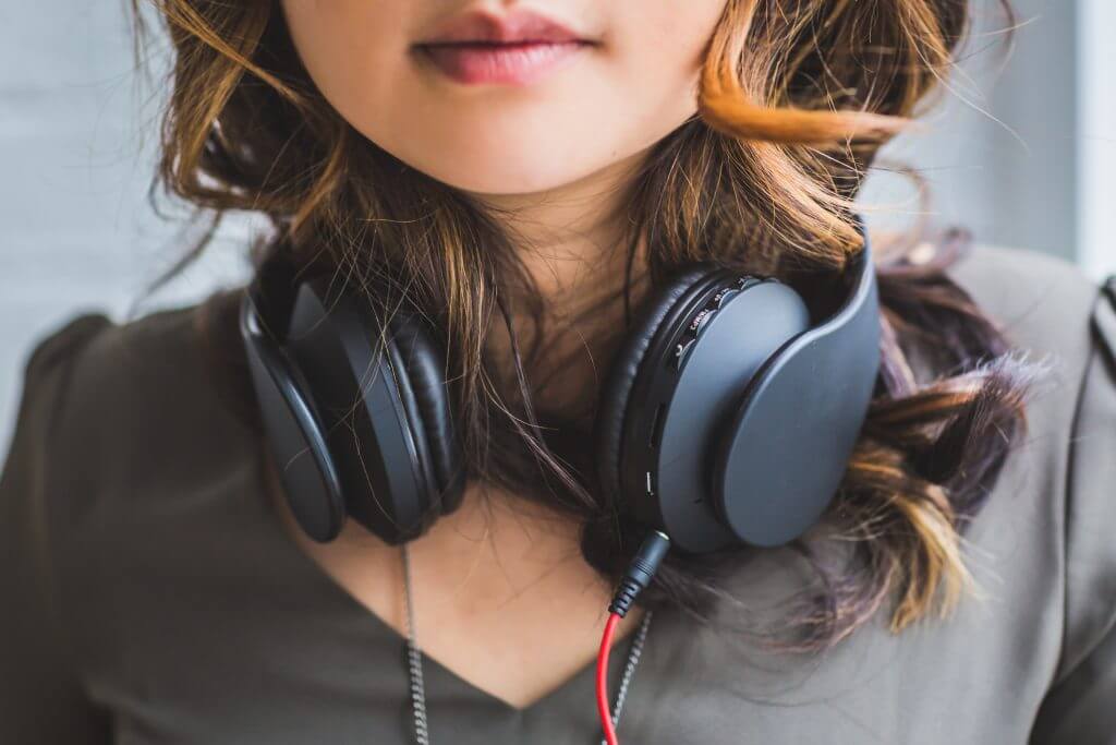 A woman with headphones listening to Podcast Guru